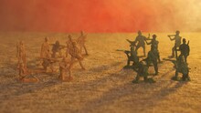 Armies Of Yellow And Green Plastic Toy Soldiers Stand Opposite Each Other In Smoke Against A Background Of Flickering Red Light. The Concept Of Military Combat Operations