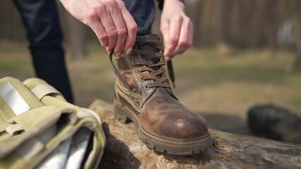 close-up female hands tying shoelaces on boot on sunny summer spring autumn day in forest. unrecogni