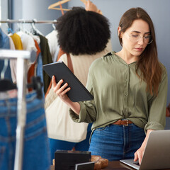 Wall Mural - Make your purchase online or in-store. Shot of a woman using a digital tablet while working in a clothing store.