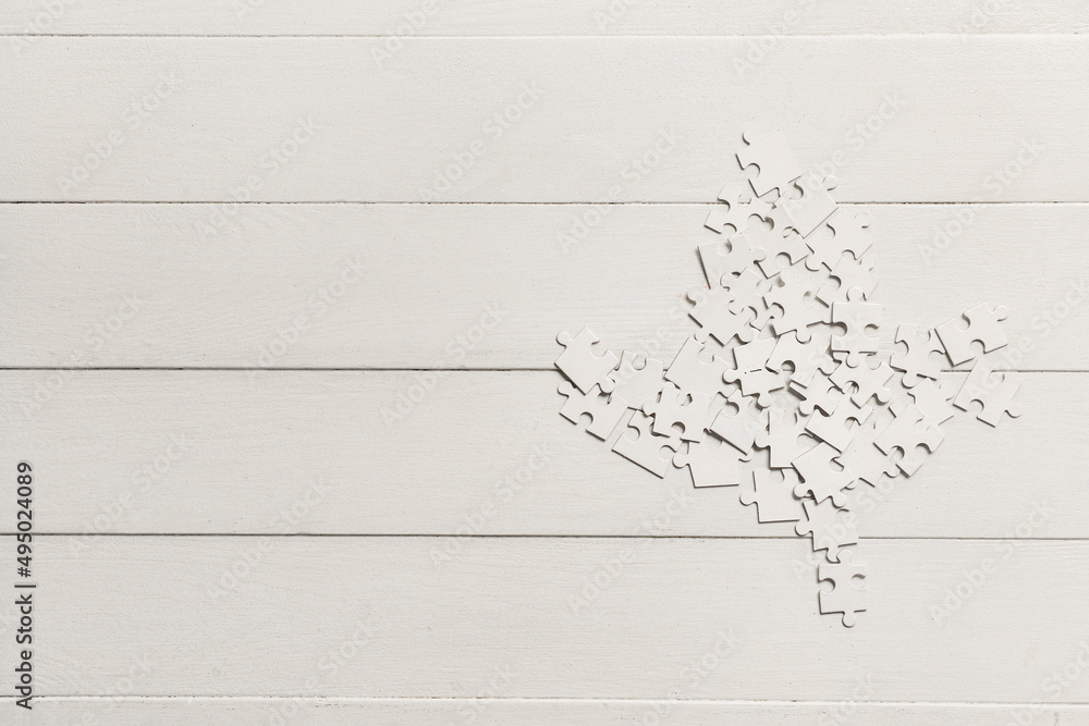 Maple leaf made of puzzle pieces on white wooden background. Canadian flag concept