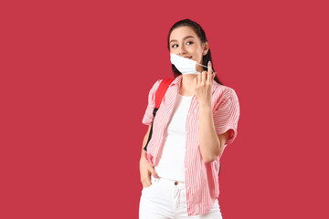 Wall Mural - Portrait of beautiful female student with face mask on color background