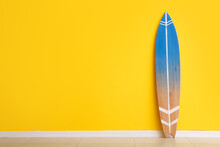 Blue Surfboard Near Yellow Wall