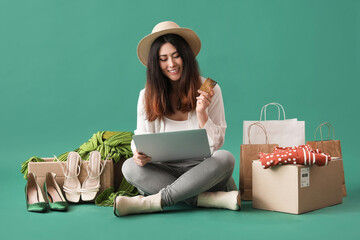 Sticker - Happy young woman with laptop, credit card and new purchases on color background. Online shopping