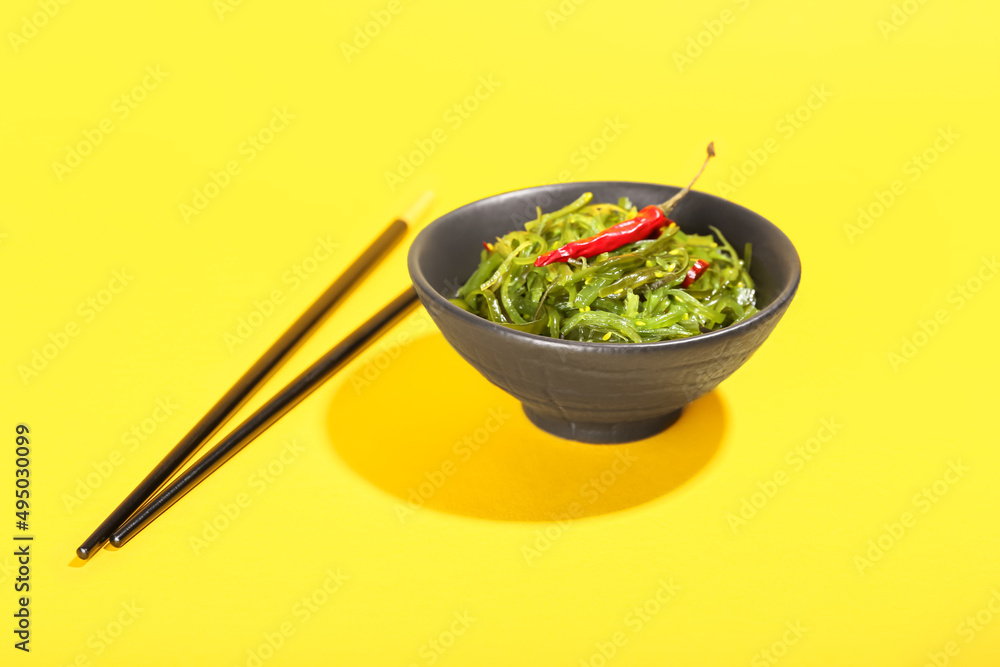 Bowl with healthy seaweed salad on yellow background
