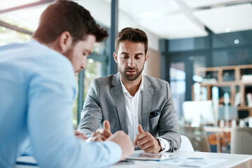 Fototapete - Digitizing a financial discussion. Cropped shot of two young businessmen using a digital tablet while going through paperwork together in a modern office.