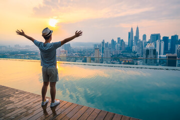 Travel man happy and raise hand up freedom enjoy view of beautiful landscape of Kuala Lumpur skyscraper in morning, Kuala Lumpur city, Malaysia.