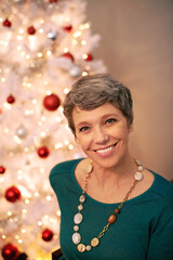 Wall Mural - Its the most wonderful time of the year. Cropped portrait of a happy mature woman sitting in front of her Christmas tree.