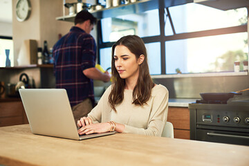 Wall Mural - The best is browsing in the comfort of your home. Cropped shot of a young woman working on a laptop with her boyfriend in the background at home.