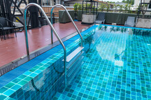 Ladder stainless handrails for descent into swimming pool. Swimming pool with handrail . Ladder of a swimming pool. Horizontal shot. stairs swimming pool. Stainless steel ladder