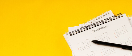 calendar month schedule to make appointment meeting or manage timetable each day lay and pen on yellow background for planning work and travel concept.