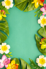 Summer background with tropical orchid flowers and green tropical palm leaves on green background. Flat lay, top view. Summer party backdrop