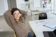 © contrastwerkstatt - young business woman with glasses sits at a desk with laptop and laughs into the camera