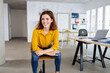 © contrastwerkstatt - young laughing woman sits in office and looks to the side