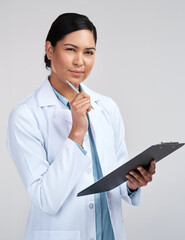 Wall Mural - This requires a little thought. Cropped portrait of an attractive young female scientist looking thoughtful while working on a clipboard in studio against a grey background.