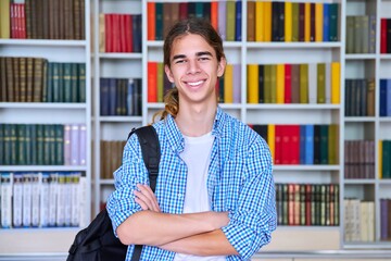 Wall Mural - Single portrait of smiling confident male student teenager looking at camera in library