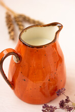 Milk In An Orange Jar, Spikelets, Herbs On White Background. Milk Pitcher For Package Design., Cream Jug