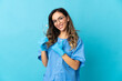 © luismolinero - Woman dentist holding tools over isolated on blue background giving a thumbs up gesture