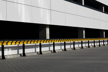 Wall Mural - Yellow and black guardrails outside building, parking lot.