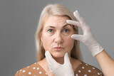 Fototapeta Koty - elderly woman doing cosmetology procedures botox injections in the forehead