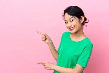 Young Vietnamese woman isolated on pink background pointing finger to the side and presenting a product