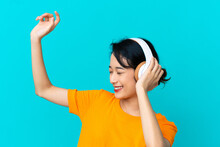 Young Vietnamese Woman Isolated On Blue Background Listening Music And Dancing