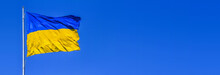 Flag Of Ukraine Waving In The Wind On Flagpole Against The Background Of A Clear Sky On Sunny Day. Horizontal Banner With Free Copy Space For Text
