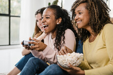 United Multiracial Young Women Playing Video Games Wit Console At Home - Diverse Female Friends Laughing Having A Great Time Together - Friendship And Entertainment Concept