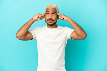 Wall Mural - Young Colombian handsome man isolated on blue background having doubts and thinking