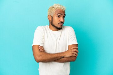 Poster - Young Colombian handsome man isolated on blue background making doubts gesture while lifting the shoulders