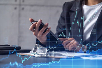 Wall Mural - A woman financial trader in formal wear is checking the phone to sign the contract to invest money in stock market. Internet trading and wealth management concept. Forex hologram chart.