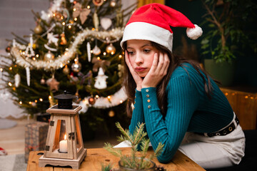 A girl sits at the table lonely and unhappy during the Christmas holidays.