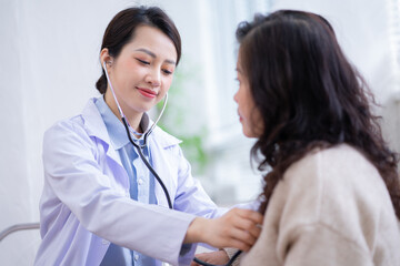 Asian female doctor examining an elderly woman at home