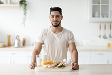 Portrait Of Attractive Young Arab Guy With Wholesome Protein Products Posing At Kitchen