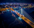 Beautiful panoramic aerial drone skyline view of the center of night Warsaw with skyscrapers in the background with the Swietokrzyski suspension bridge - the lights of the big city by night, Poland