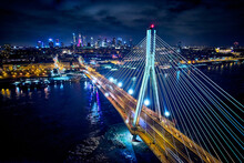 Beautiful Panoramic Aerial Drone Skyline View Of The Center Of Night Warsaw With Skyscrapers In The Background With The Swietokrzyski Suspension Bridge - The Lights Of The Big City By Night, Poland
