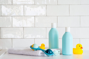 Wall Mural - Toiletries baby on tile background. Baby shower gel and shampoo bottle with toy, towel and yellow ducks.