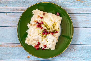 Wall Mural - Gullac dessert on wooden background. Traditional Ramadan dessert. Güllaç dessert decorated with pistachio and pomegranate. Turkish cuisine delicacies. Top view