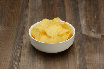 Canvas Print - Patatas fritas o chips en un bol de cerámica blanca sobre fondo la mesa marrón