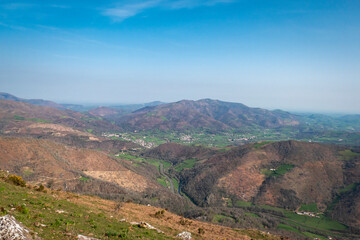 Vista panorâmica a partir da montanha Jara no País Basco com as montanhas ao fundo, verdes pastos e parte das cidades à volta