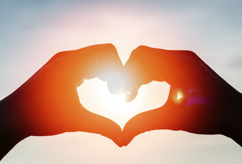 love romance background concept. hand heart shape with sunset sky with lover silhouette on the beach