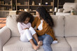 © fizkes - Joyful happy African mom tickling excited daughter girl on couch, playing with child at home, enjoying active games, motherhood, having fun, laughing, giggling. Family, parenthood concept.