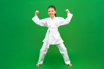 Wall Mural - A child in a kimono on a green background. The girl fighter shows different techniques.