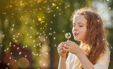 Fototapeta Dmuchawce - curly girl blowing dandelion