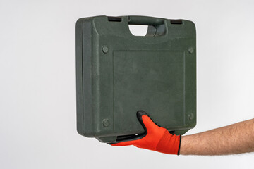 Toolbox in men's hands. The plastic tool case is isolated on a white background. Construction and repair. Home master tool. Black box for tool. Repair accessories