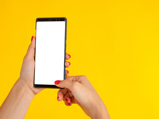 Wall Mural - Women's hands are holding a smartphone with blank screen. Big phone in female hands. Place for text, advertising, ads on the mobile phone screen. Well-groomed female hands with a phone.