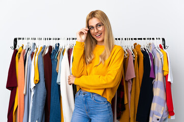 Canvas Print - Young Uruguayan blonde woman in a clothing store with glasses and happy