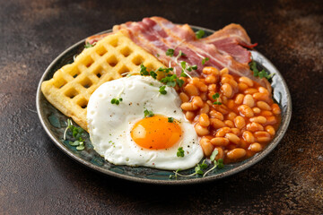 Wall Mural - Potato waffles with fried egg, bacon and baked beans. Morning breakfast