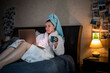 © phpetrunina14 - woman laying down in bed with wet head covered with towel working on laptop