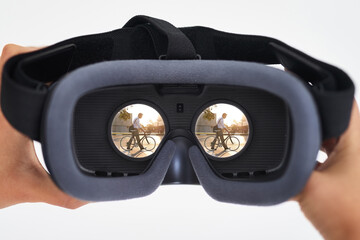 Sticker - The age of virtual reality is here. Shot of a person holding a VR headset with a man riding a bicycle seen in the lenses.