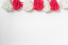 Brushes From Yarn Of Red And White Color On A White Background. Space For Copy Space. DIY Yarn Brushes. Garland. Garland Of Yarn. Pampushki From Yarn. Children's Creativity